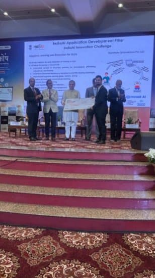 Award ceremony on stage at the IndiaAI Innovation Challenge, in front of a slide titled IndiaAI Application Development Pillar showing the mvaak AI name.